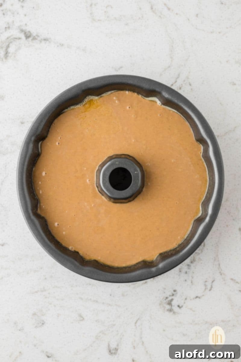 Spiced Molasses Bundt Cake 9 Smooth gingerbread cake batter being carefully poured into a meticulously prepared bundt cake pan, poised for baking.
