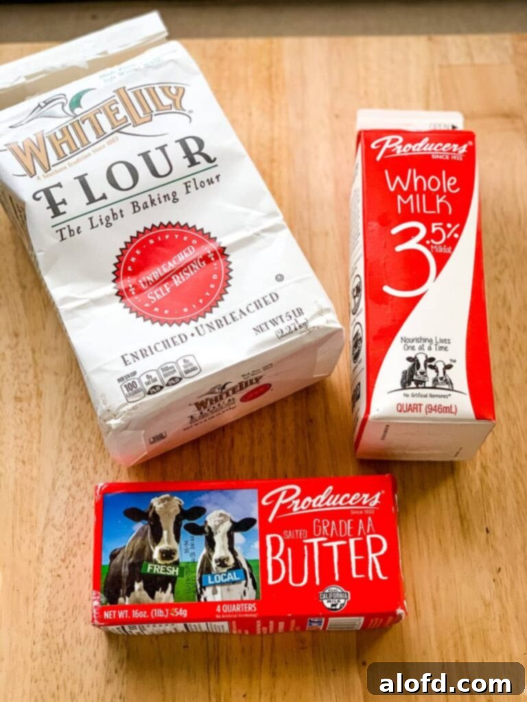 Milk, butter, and self rising flour laid out on a wooden surface, ready for making delicious drop biscuits.