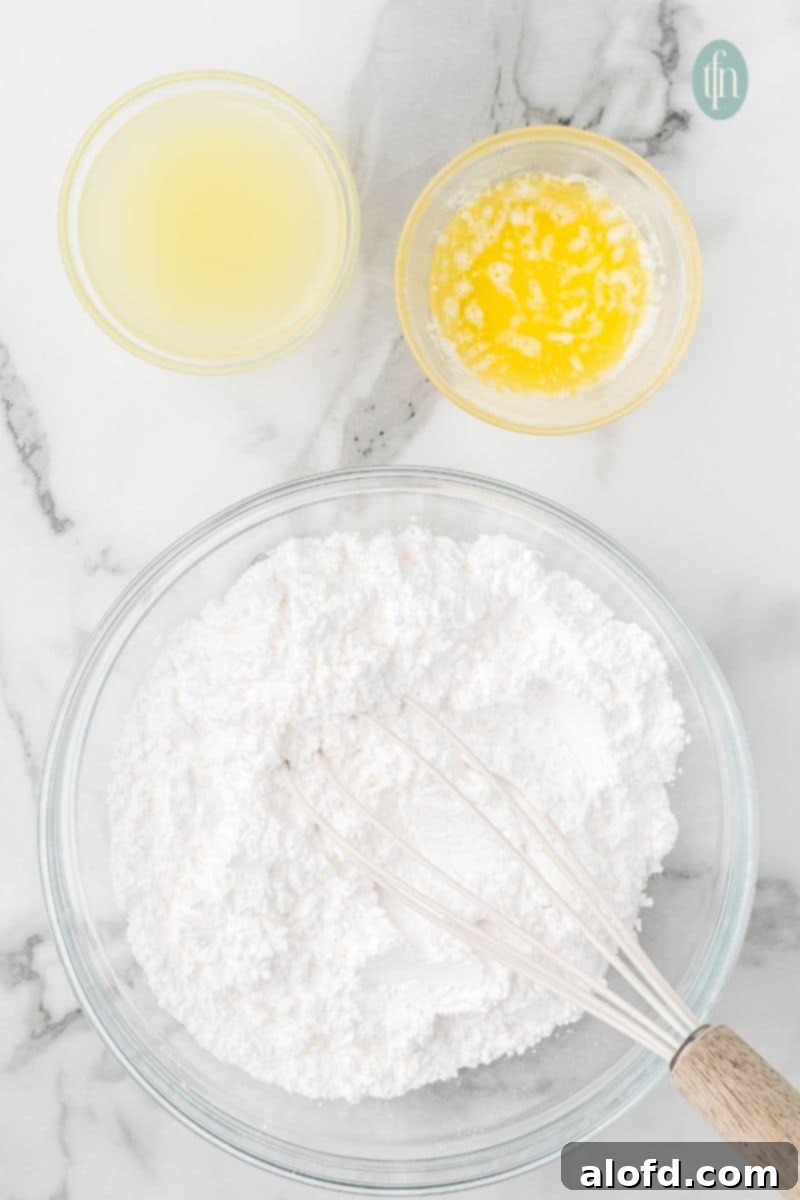 A bowl of powdered sugar with whisk and a bowl of lemon juice and butter.