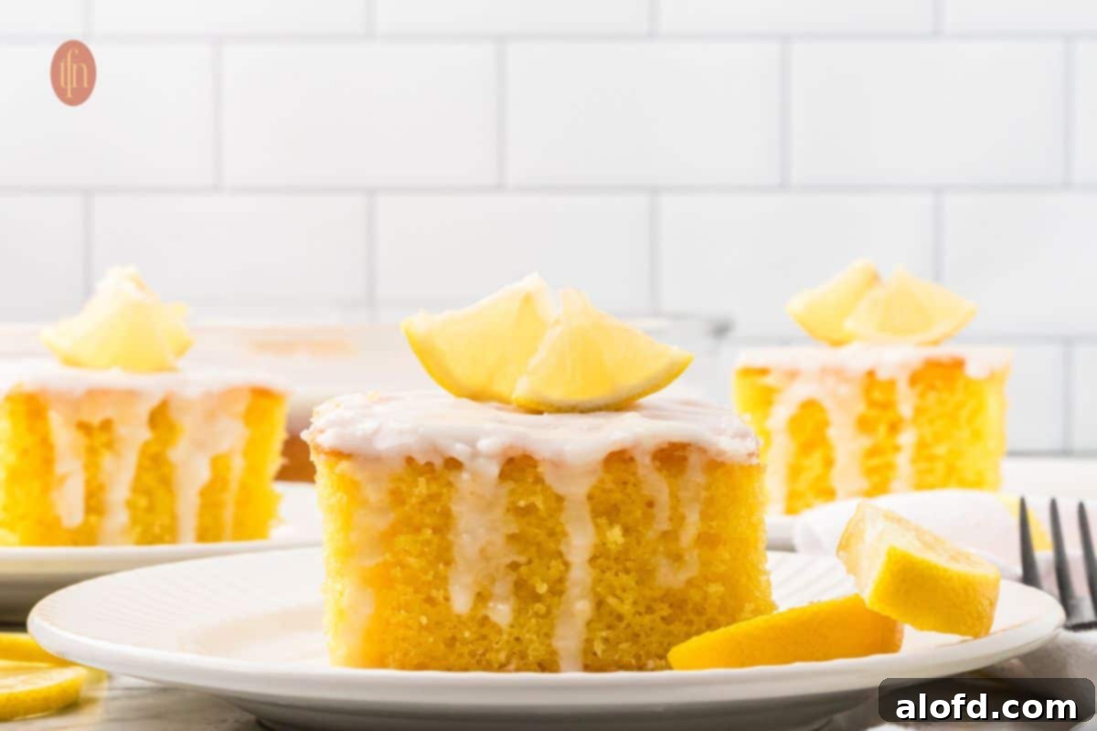 A slice of cake with white glaze and slice of lemon on top.