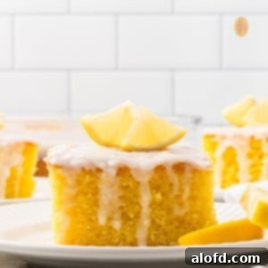 A slice of cake with white glaze and slice of lemon on top.
