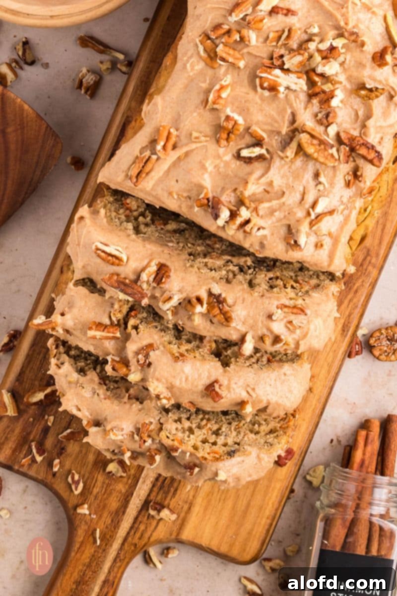 Farmhouse Carrot Cake Loaf 2 Sliced loaf with frosting topped with nuts.