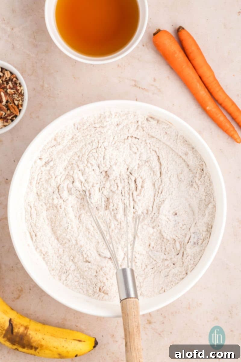 Farmhouse Carrot Cake Loaf 11 A bowl of flour mixture with whisk.