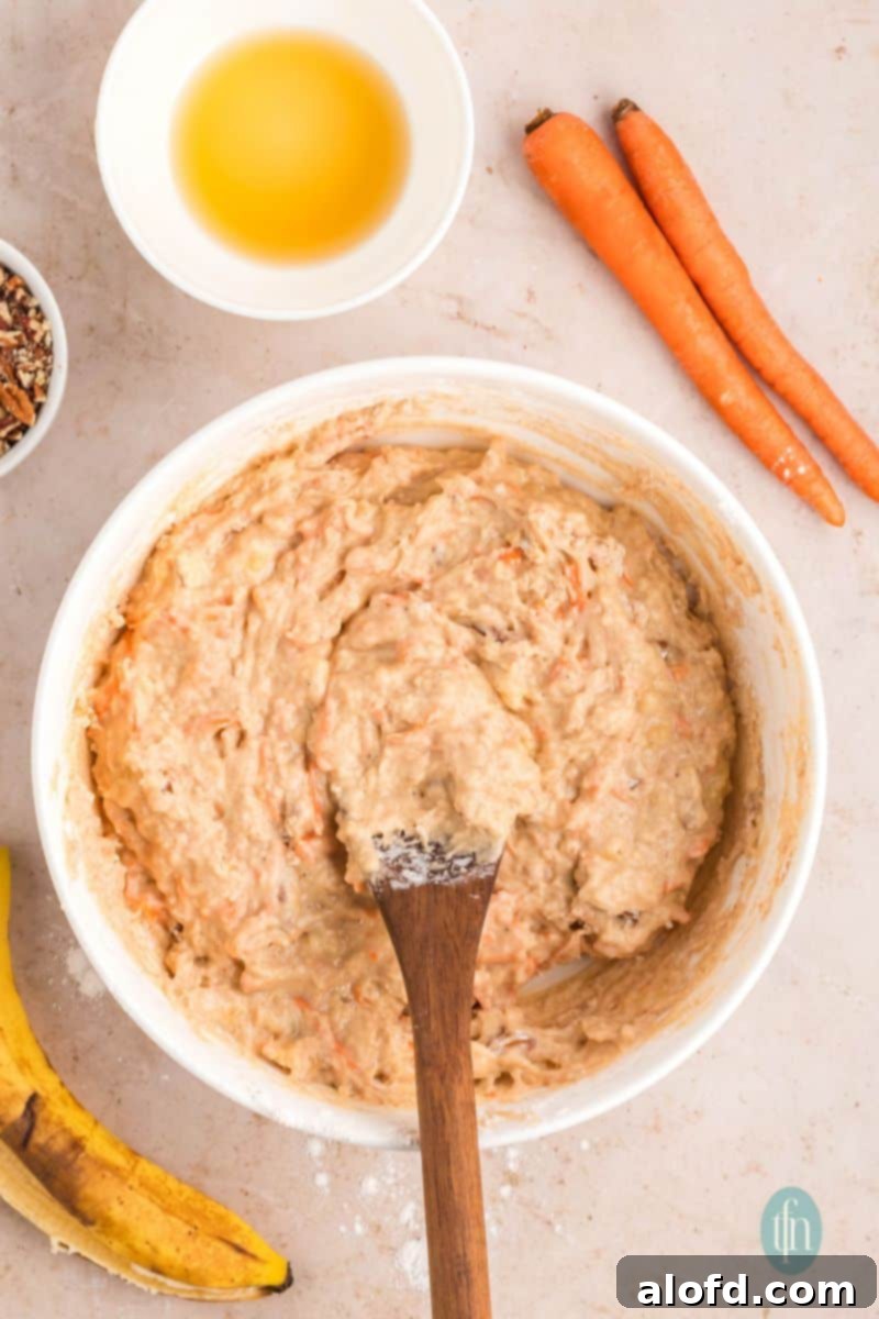 Farmhouse Carrot Cake Loaf 16 Batter mixture in a bowl with wooden spoon.