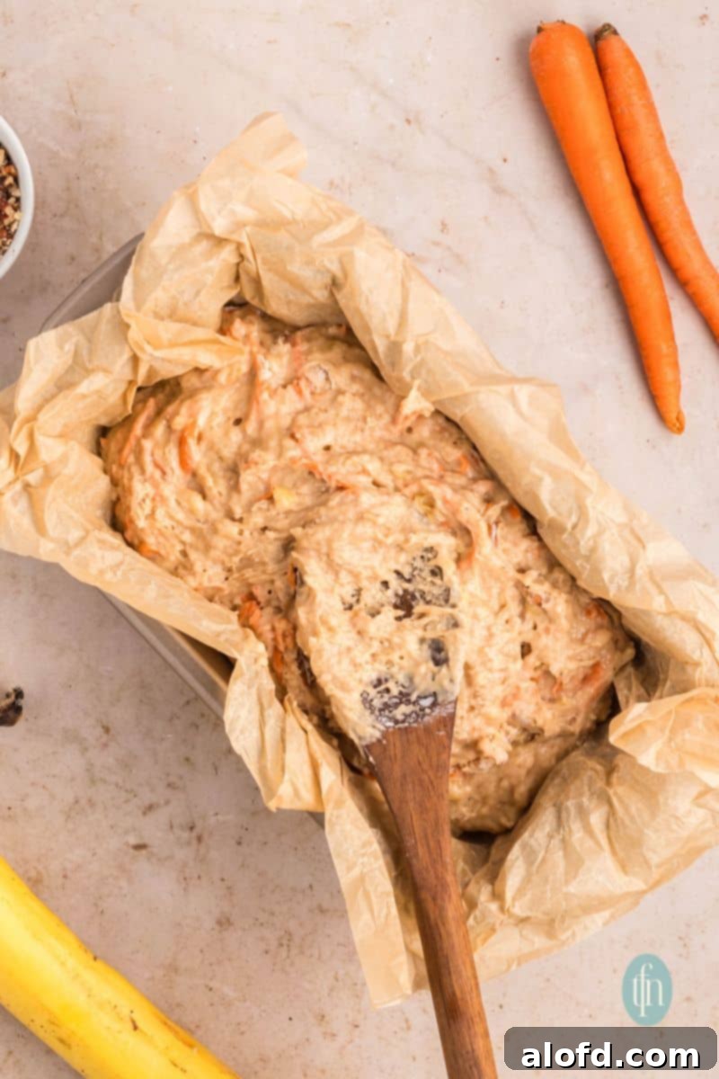 Farmhouse Carrot Cake Loaf 17 Batter mixture in a loaf pan with parchment paper.