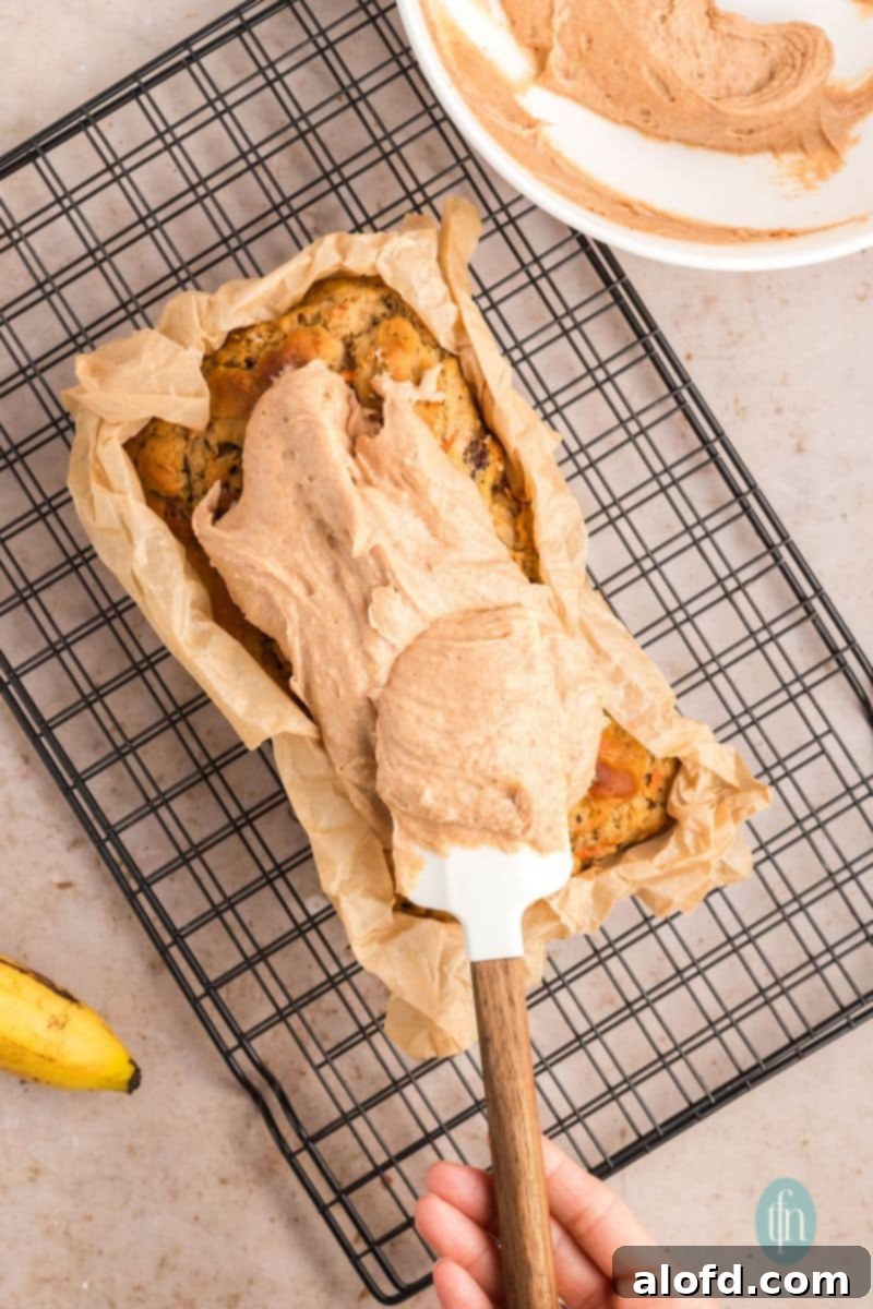 Farmhouse Carrot Cake Loaf 21 Spreading frosting on top of a pan of loaf.