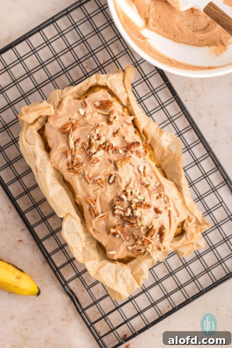 Farmhouse Carrot Cake Loaf 23 A pan of loaf with frosting topped with nuts.