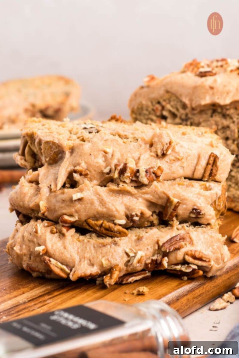 Farmhouse Carrot Cake Loaf 4 Sliced loaf with frosting topped with nuts.