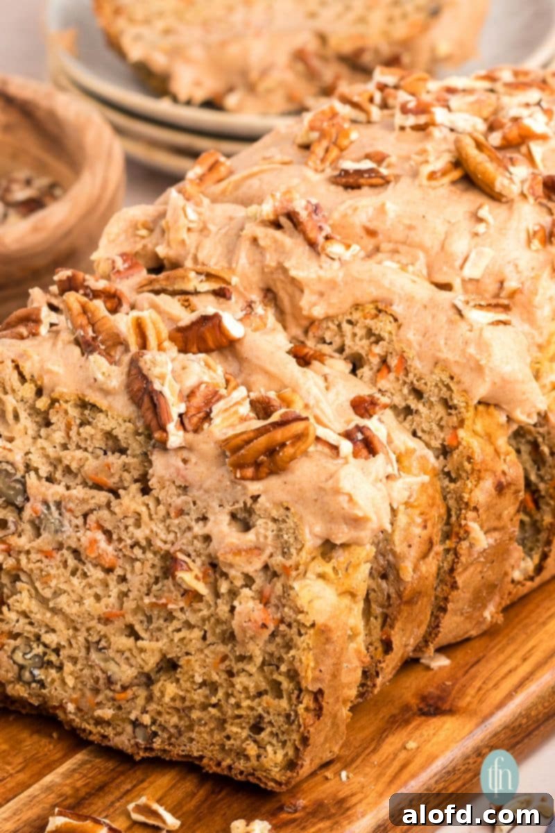 Farmhouse Carrot Cake Loaf 7 Sliced loaf with frosting topped with nuts.
