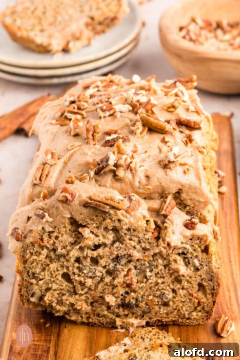 Farmhouse Carrot Cake Loaf 8 loaf with frosting topped with nuts.