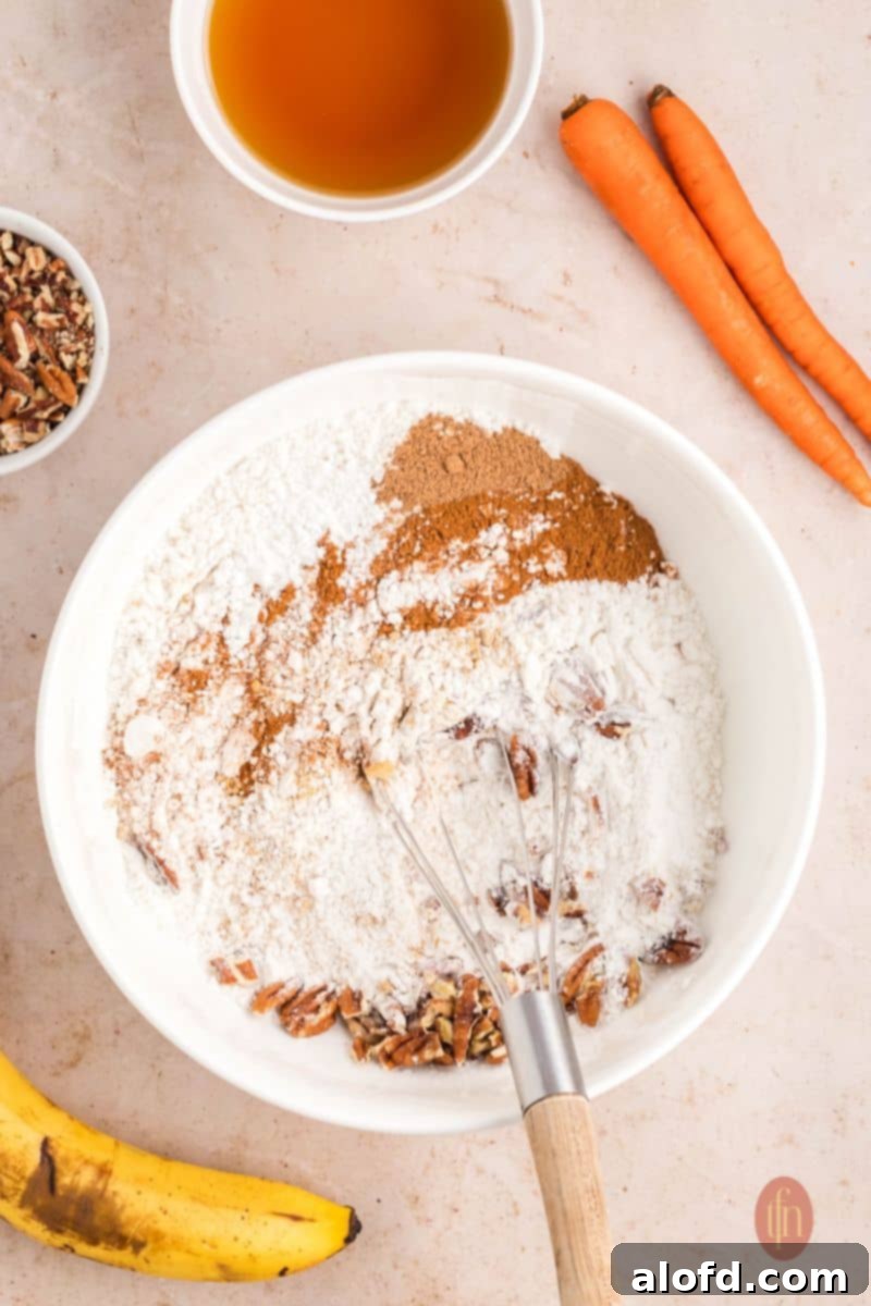 Farmhouse Carrot Cake Loaf 10 A bowl of flour mixture with whisk.