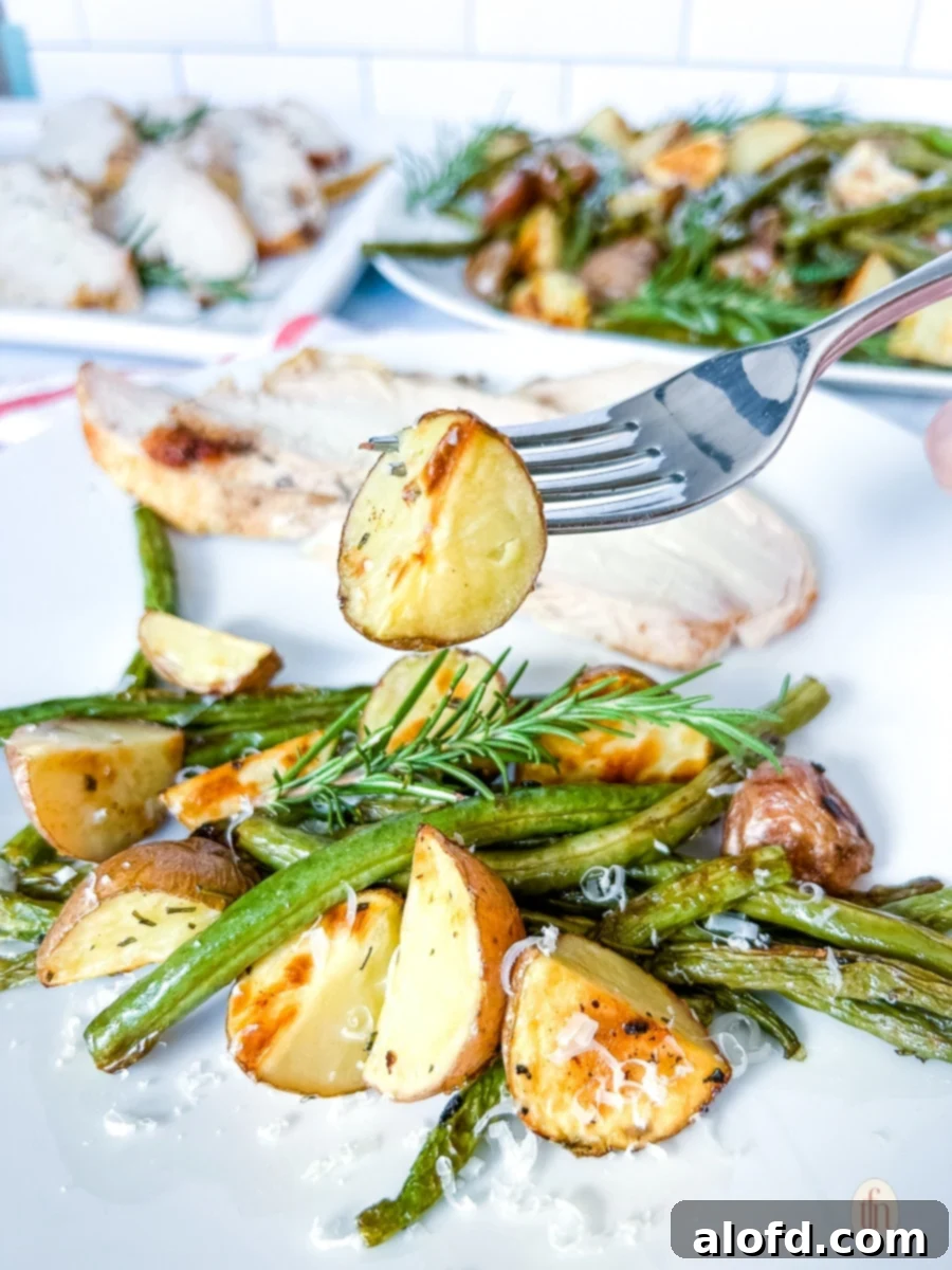 Comforting February Dinners: 20+ Recipes 3 A fork holding a perfectly roasted potato, with a blurred plate of assorted roasted vegetables and green beans in the background.