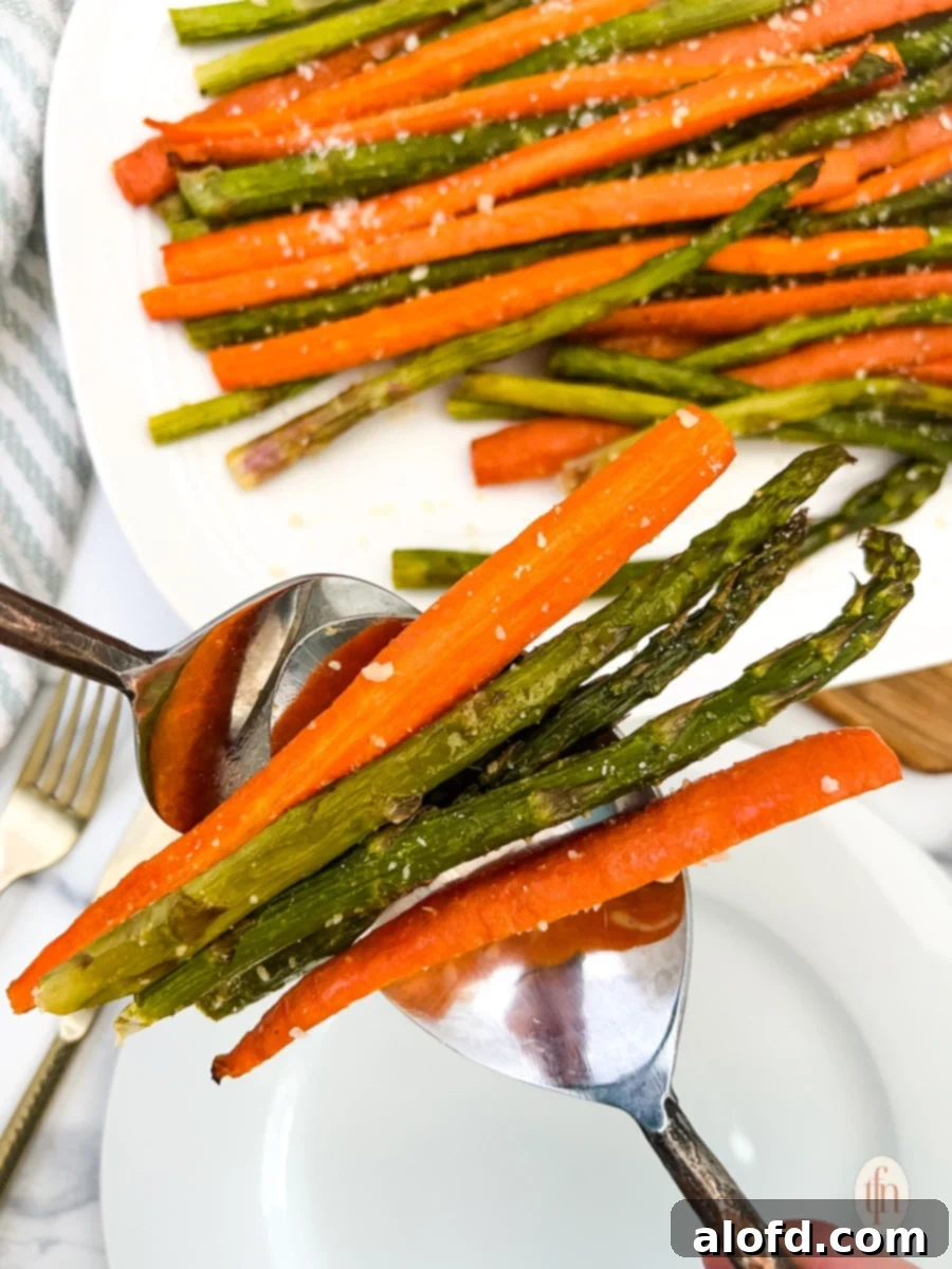 Comforting February Dinners: 20+ Recipes 9 Two spoons retrieving a serving of perfectly roasted carrots and asparagus, ready to be placed on a plate.