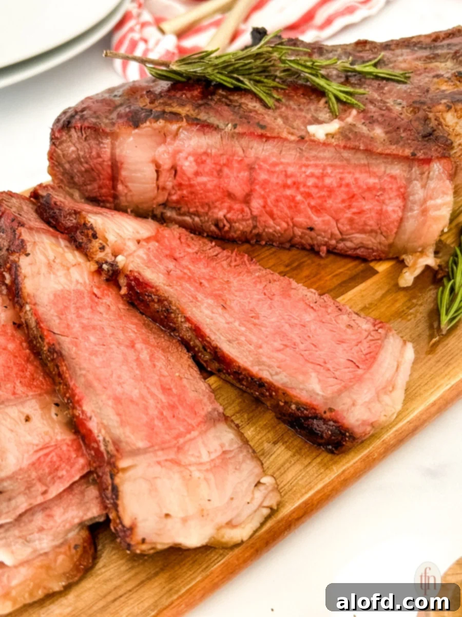 Expertly sliced cowboy ribeye steak, revealing its juicy interior, elegantly presented on a rustic wooden cutting board.