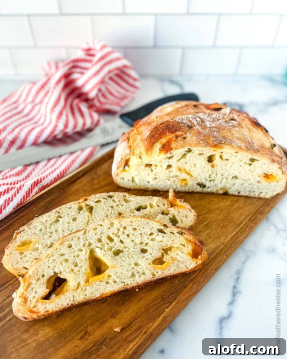 March Flavor Feast: Irresistible Dinner Ideas 26 Beautifully sliced jalapeno cheddar sourdough bread artfully arranged on a wooden board, with the whole rustic loaf blurring gently in the background, accompanied by a charming red and white towel.