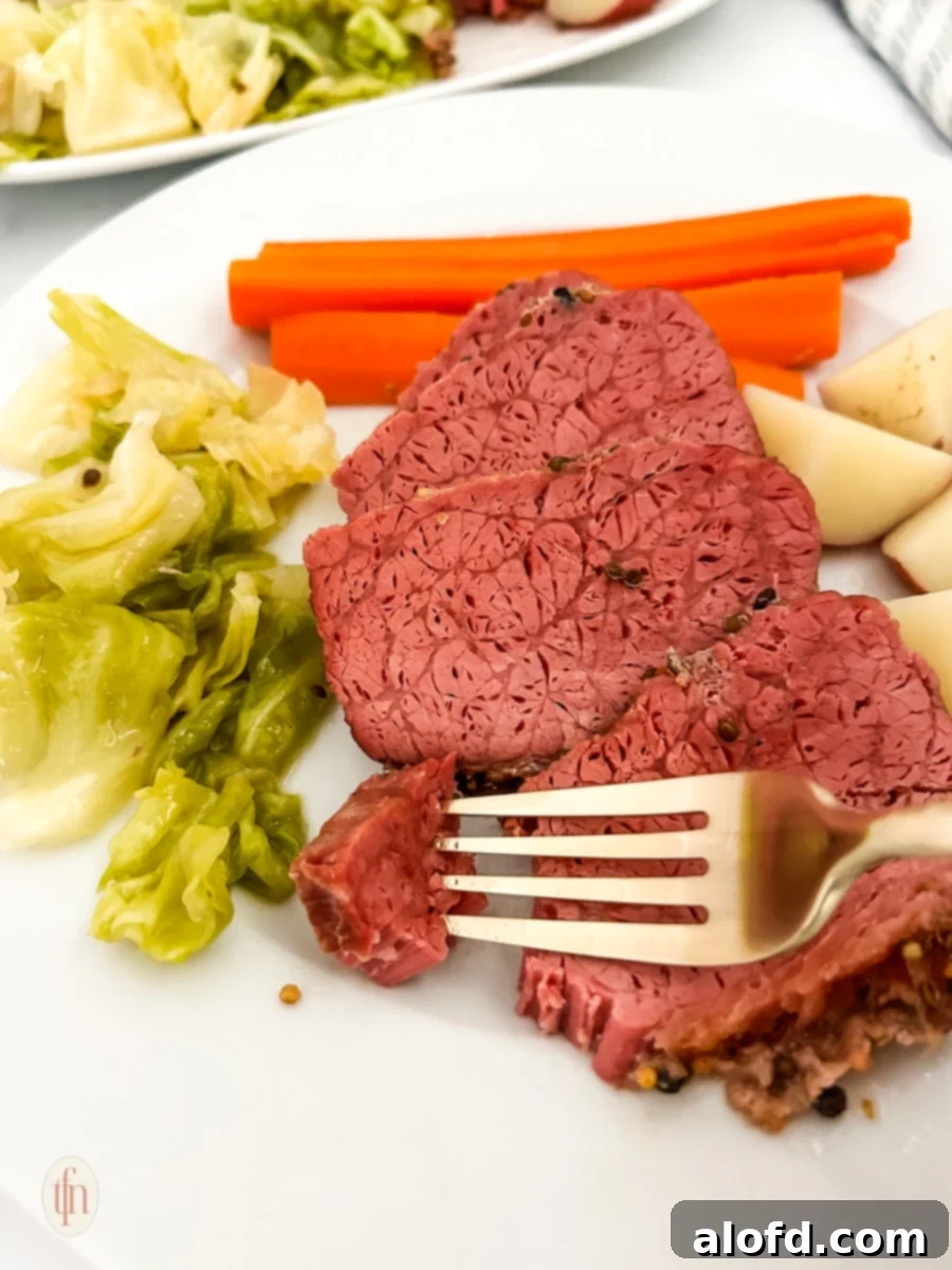 March Flavor Feast: Irresistible Dinner Ideas 4 Hearty Dutch oven corned beef with tender vegetables arranged on a white plate, accompanied by a fork.