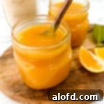 March Flavor Feast: Irresistible Dinner Ideas 33 Two elegant jars of vibrant Meyer lemon curd, one with a spoon resting on top, displayed on a rustic wooden board adorned with fresh lemon slices.