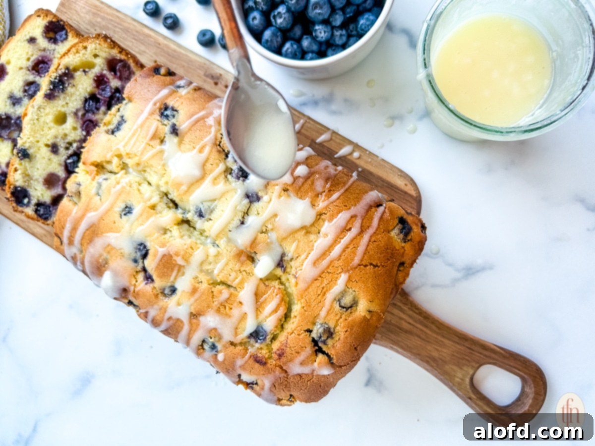 March Flavor Feast: Irresistible Dinner Ideas 36 A close-up of a hand delicately spooning a smooth powdered sugar glaze over a freshly baked blueberry pound cake.