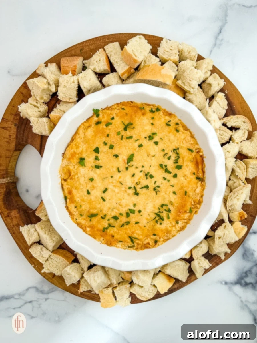 March Flavor Feast: Irresistible Dinner Ideas 9 A visually appealing bowl of creamy Cajun crab dip with shrimp, artfully arranged with croutons on a rustic wooden platter.