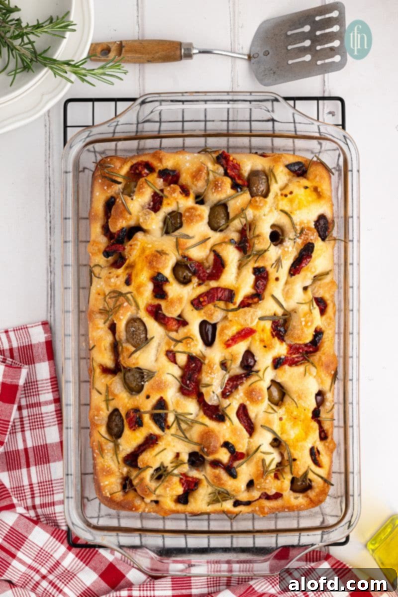 Freshly baked sourdough focaccia bread in a glass baking pan, golden and inviting.