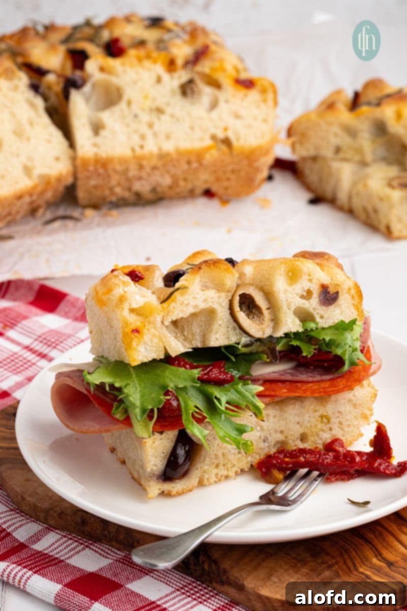 A perfectly baked slice of sourdough focaccia bread on a white plate with a fork.
