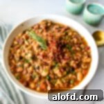 square photo of a white bowl with 15 bean soup with a striped kitchen cloth and a golden spoon at the side, inviting to a hearty meal.