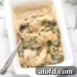 A white casserole serving dish with smothered chicken, ready to be served.