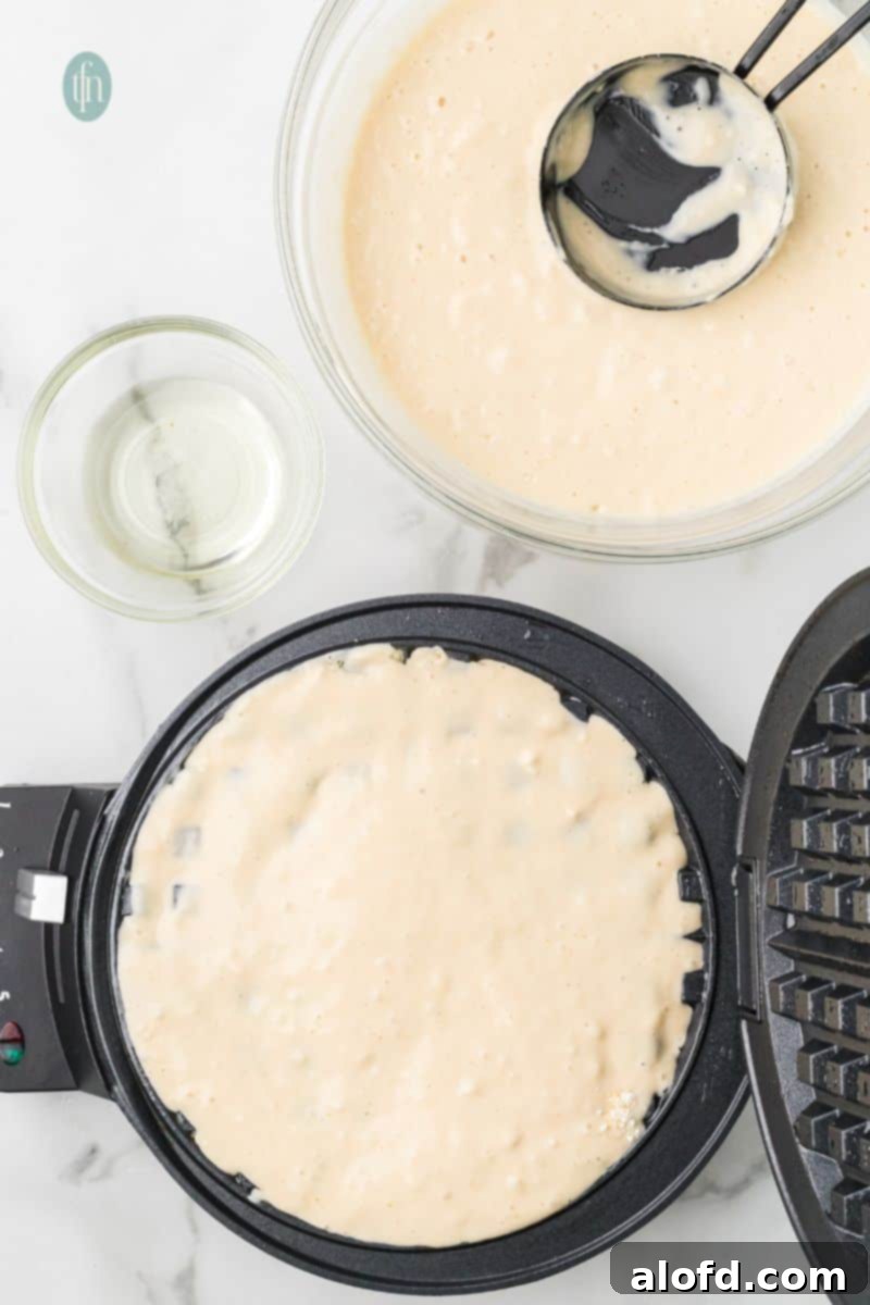 Fluffy Golden Bisquick Waffles 12 A batter mixture on a waffle maker.