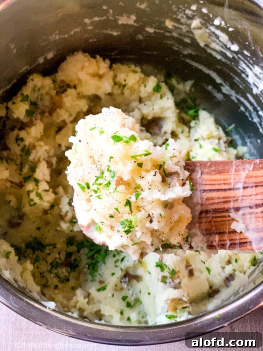 Foolproof Instant Pot No-Drain Mash 8 A wooden spoonful of mashed potatoes garnished with fresh parsley.