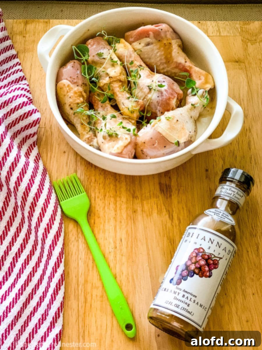 a bowl of chicken drumsticks with a bottle of balsamic dressing marinade
