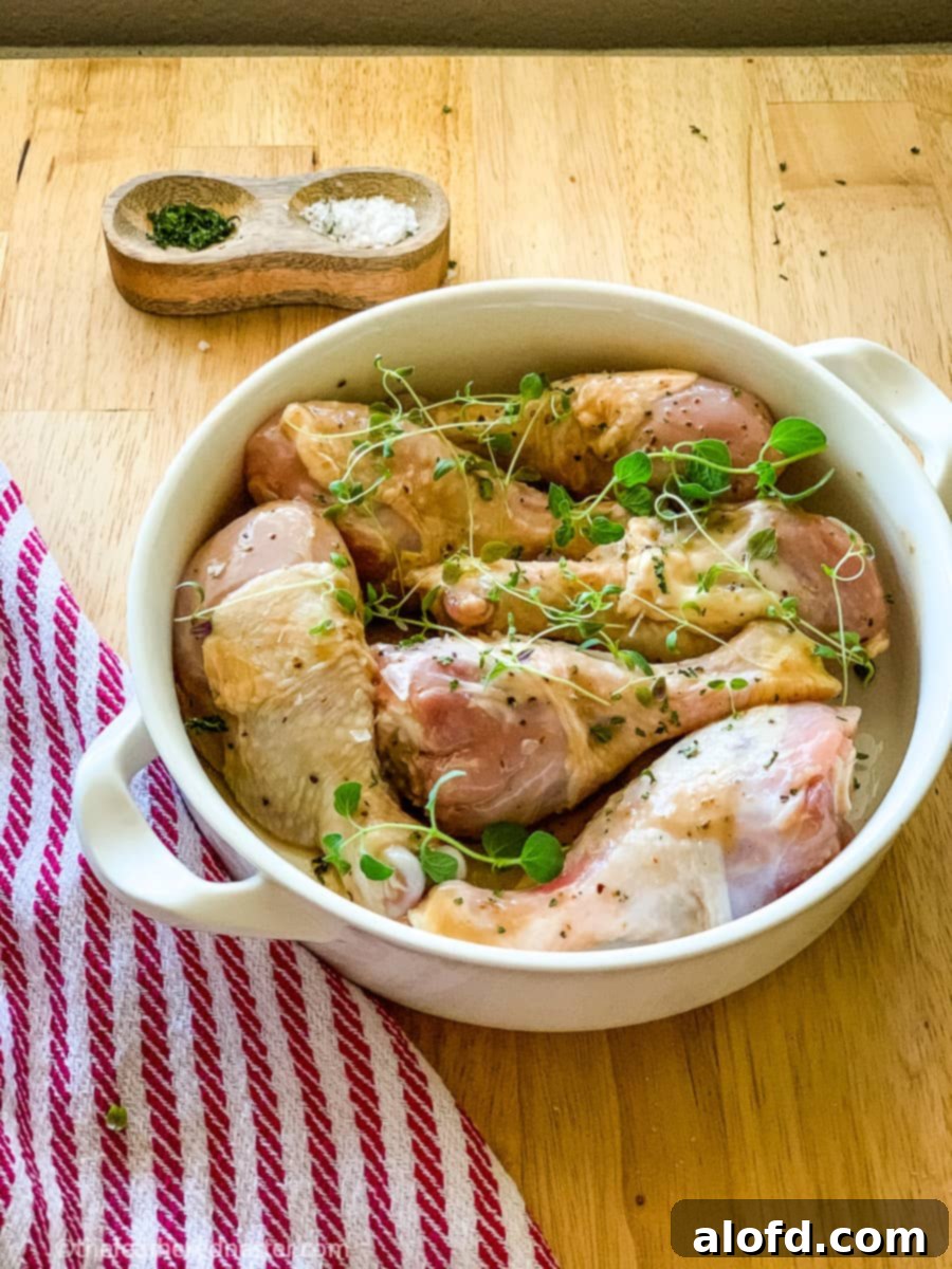 a bowl with balsamic marinated drumsticks ready to bake on a sheet pan