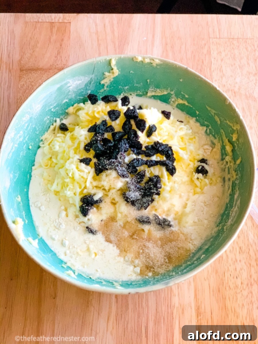 A green bowl filled with cream, nuts, and dried fruit, ready for scone preparation.