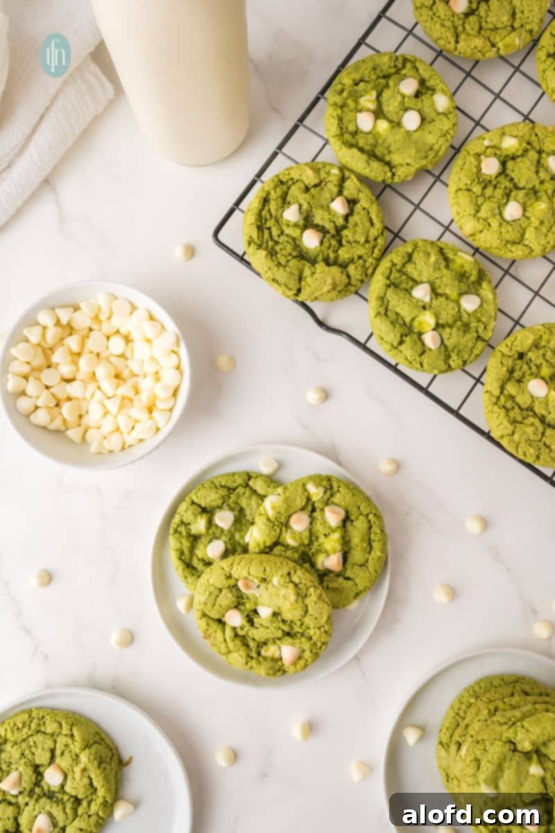 Vibrant Matcha White Chocolate Cookies 6 A plate brimming with green matcha white chocolate cookies, scattered with extra white chocolate chips for visual appeal.