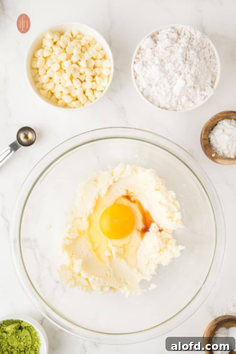 Vibrant Matcha White Chocolate Cookies 8 Creamed butter and sugar mixture in a bowl with an egg, ready to be mixed.