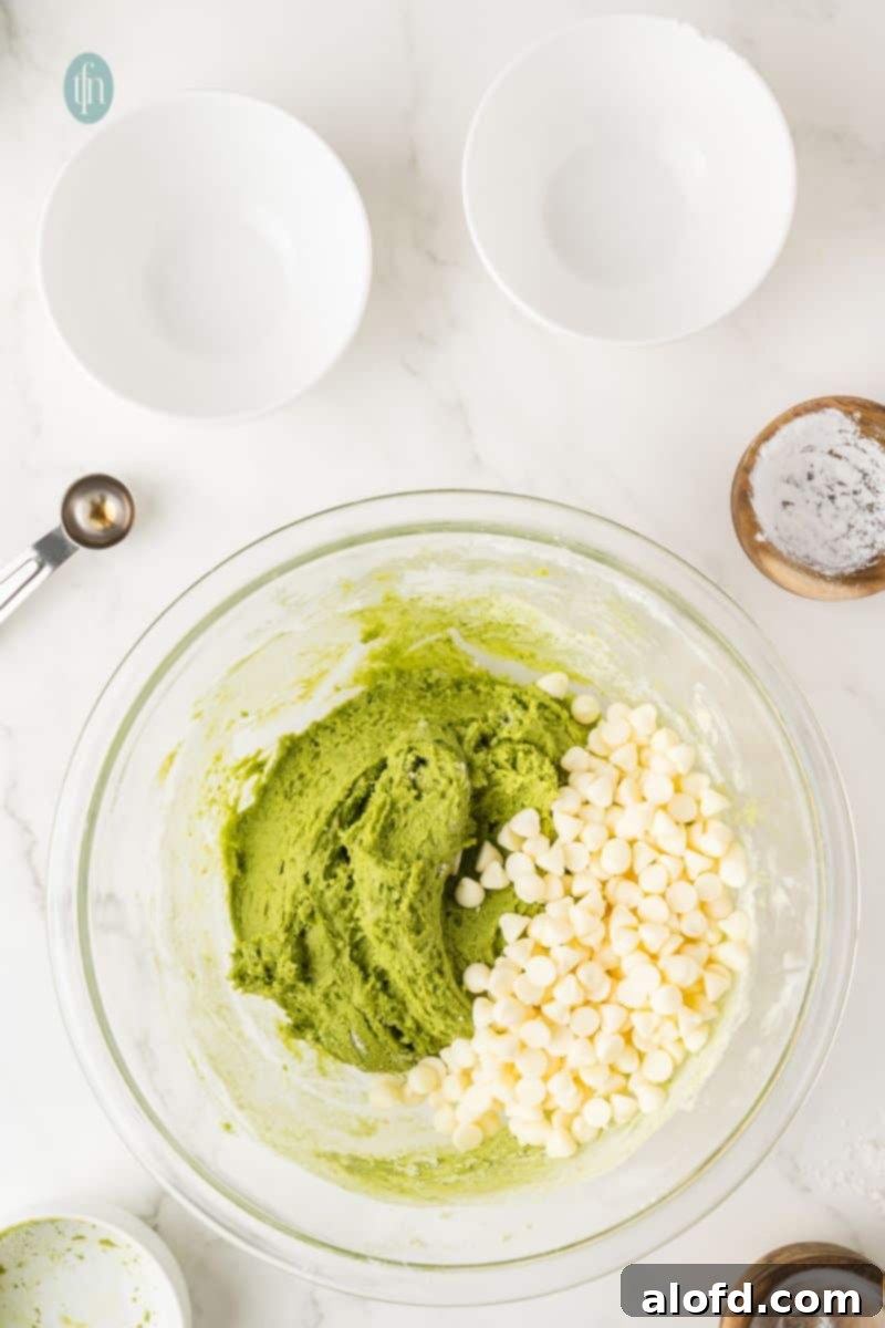 Vibrant Matcha White Chocolate Cookies 10 Green cookie dough mixed with white chocolate chips in a bowl, ready for scooping.