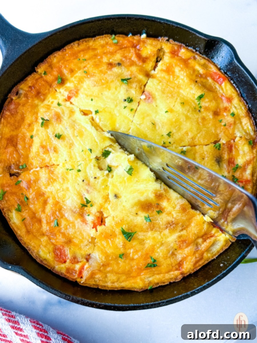 A serving knife elegantly slicing into a fluffy frittata, showcasing its savory layers.