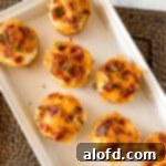 A square photograph showcasing a pristine white tray elegantly displaying a batch of golden-brown hash brown breakfast cups.
