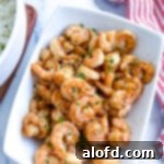 Delectable Blackstone hibachi shrimp artfully arranged on a pristine white platter, perfectly complemented by a small bowl of fluffy white rice.