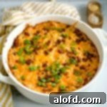 A golden casserole dish overflowing with loaded Hashbrowns, with a charming striped yellow cloth subtly enhancing the background.