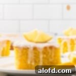 A generous slice of lemon poke cake adorned with delicate white glaze and a fresh lemon slice on top.