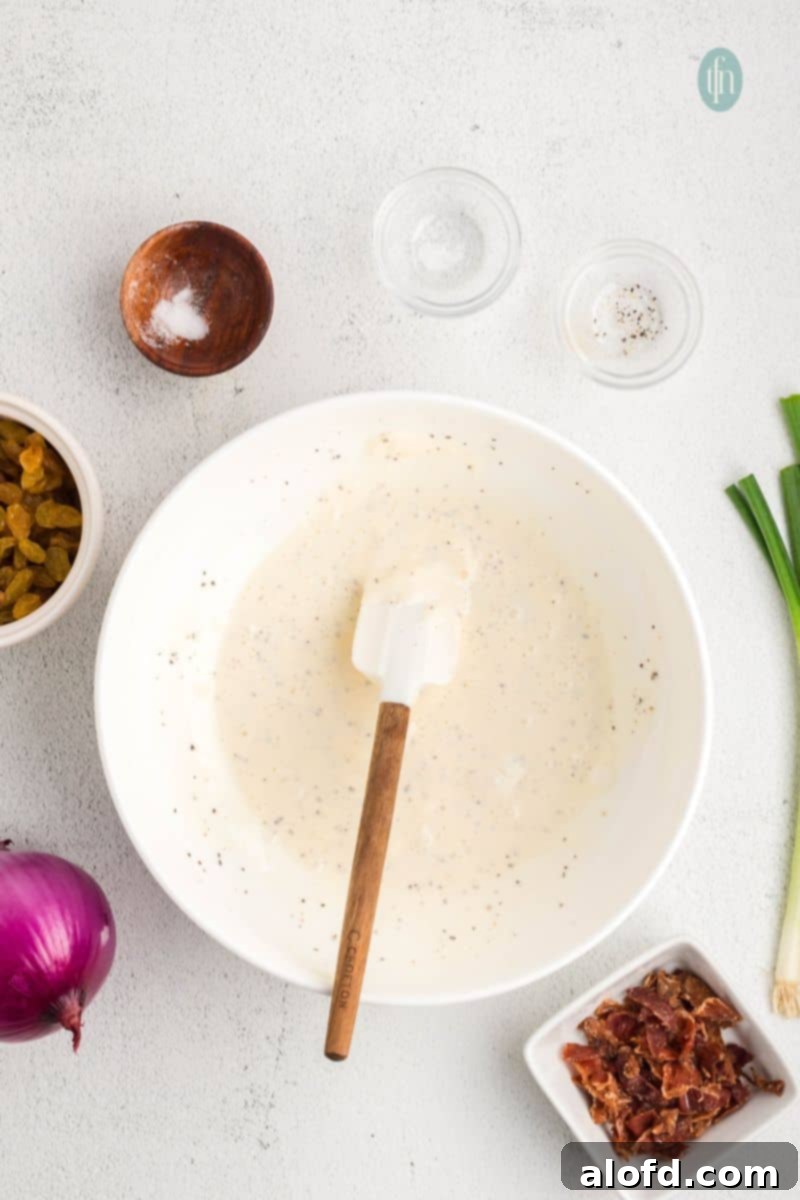 A close-up of the smooth, creamy dressing in a white mixing bowl, ready for the other salad ingredients.