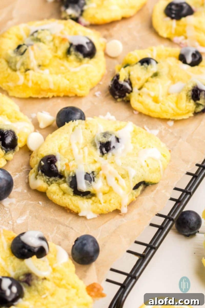 Lemon Blueberry Bliss Bites 2 Glazed lemon blueberry cake cookies on a cooling rack over parchment paper.