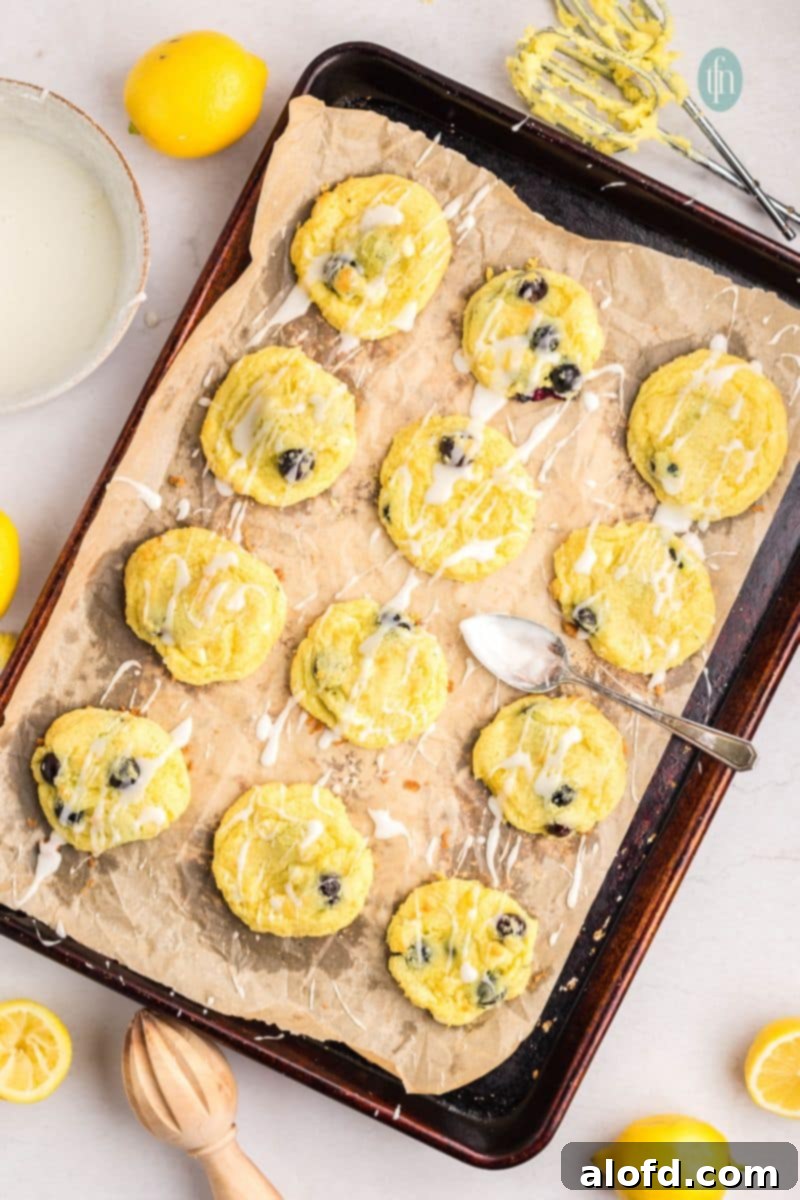 Lemon Blueberry Bliss Bites 18 Baked cookies with lemon glaze applied on a baking sheet.