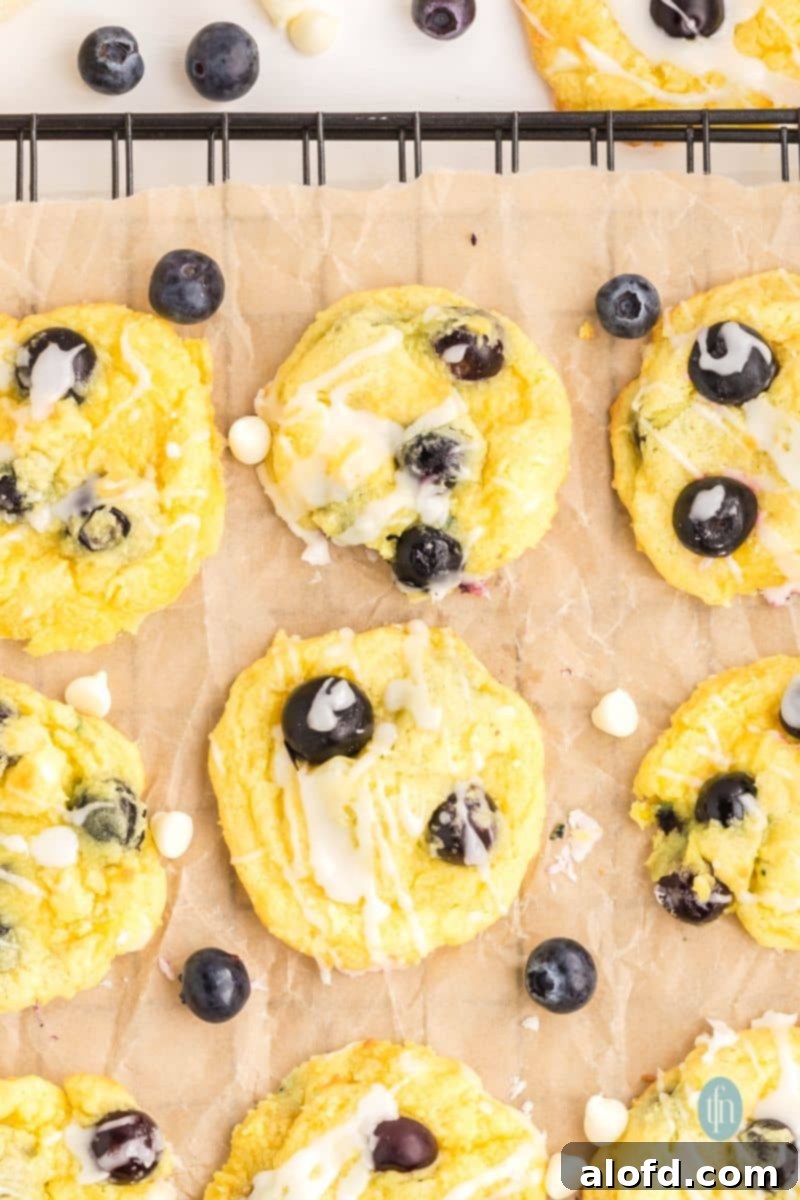 Lemon Blueberry Bliss Bites 4 Glazed lemon blueberry cake cookies on a cooling rack with parchment paper.