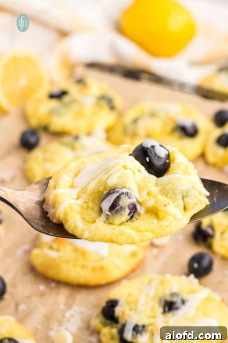Lemon Blueberry Bliss Bites 6 A single lemon blueberry cake cookie with glaze and visible blueberries.