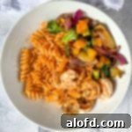 Light and Vibrant Spring Dinners 23 a white plate of Blackstone Vegetables with pasta and shrimp.