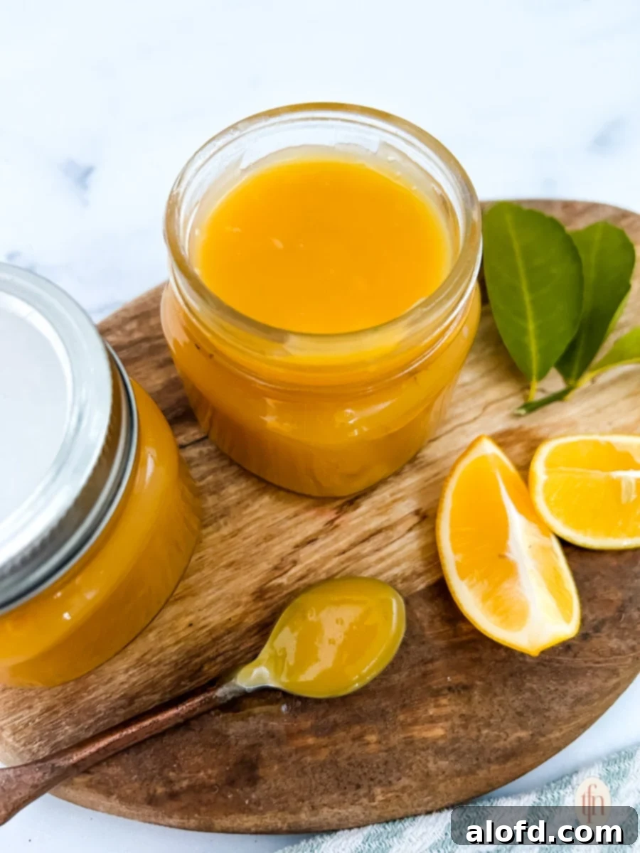 Light and Vibrant Spring Dinners 31 Two jars of meyer lemon curd with spoon on top of a wooden board with slices of lemon.