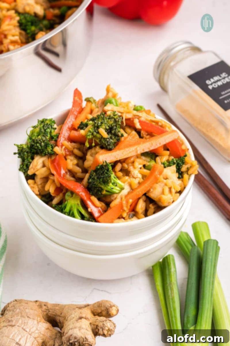 A vibrant bowl of teriyaki chicken and rice, garnished with fresh green onions and sesame seeds.
