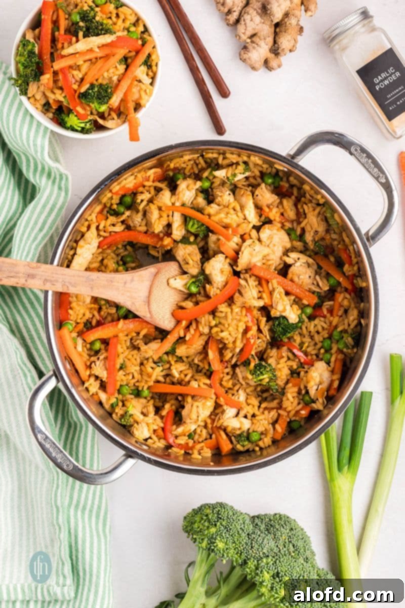 The delicious chicken and rice bowl simmering gently in a pan, steam rising.