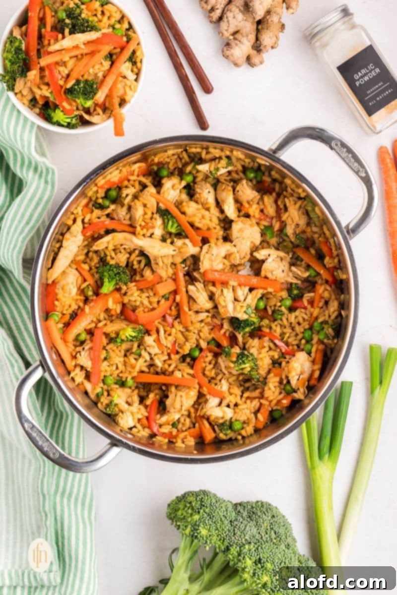 A large pan filled with freshly cooked teriyaki chicken and rice, mixed with colorful vegetables.